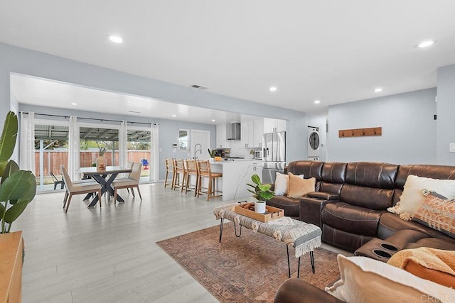 living room with stacked washer / drying machine and light wood-type flooring