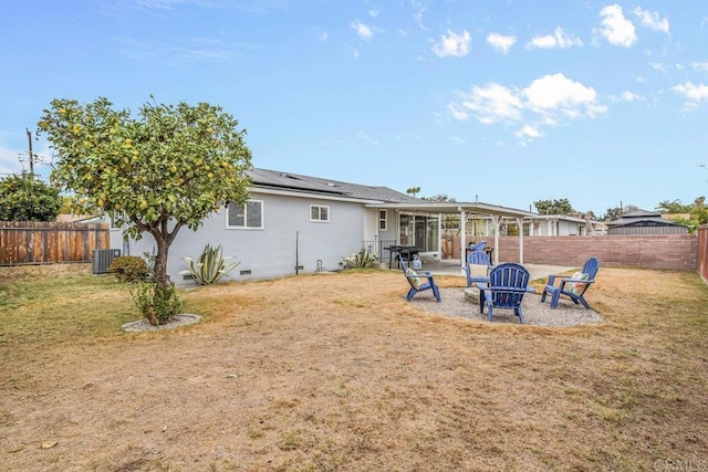 rear view of property featuring cooling unit, a yard, and a fire pit