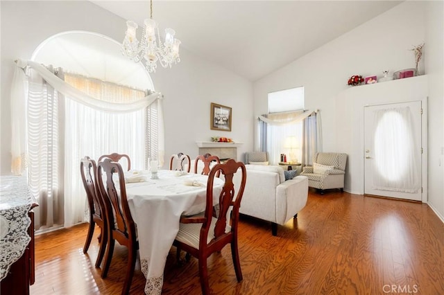 dining room featuring hardwood / wood-style flooring, an inviting chandelier, and vaulted ceiling