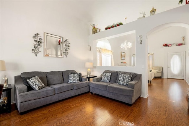 living room with wood-type flooring, a chandelier, and a high ceiling