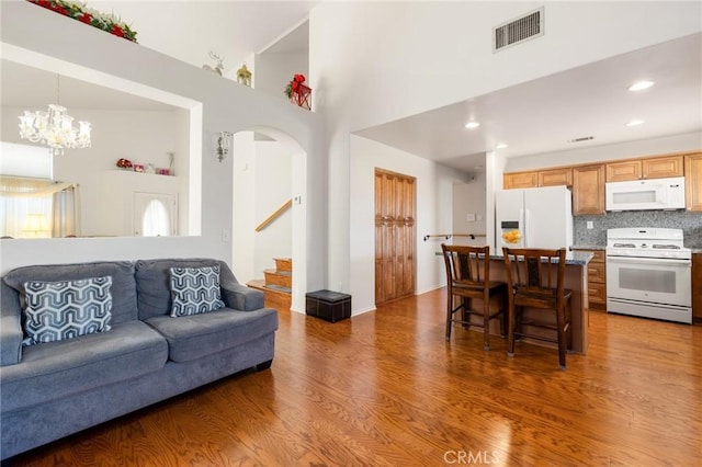 living room with a towering ceiling, an inviting chandelier, and dark hardwood / wood-style floors