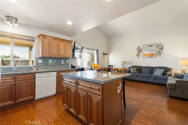 kitchen with dishwasher, a kitchen island, dark wood-type flooring, tasteful backsplash, and a kitchen breakfast bar