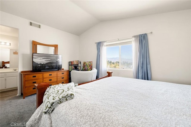 bedroom with carpet floors, ensuite bath, and lofted ceiling