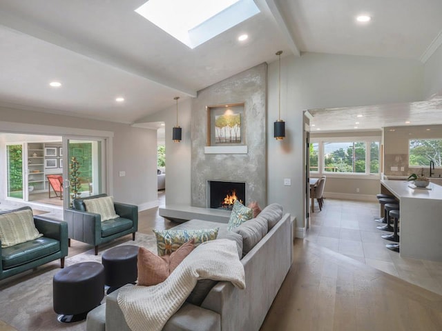 living room featuring a large fireplace, lofted ceiling with skylight, and light wood-type flooring