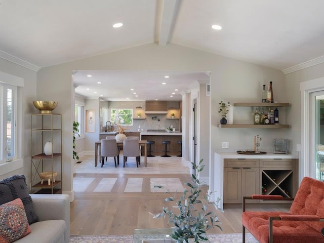 living room with lofted ceiling with beams, light hardwood / wood-style flooring, and ornamental molding