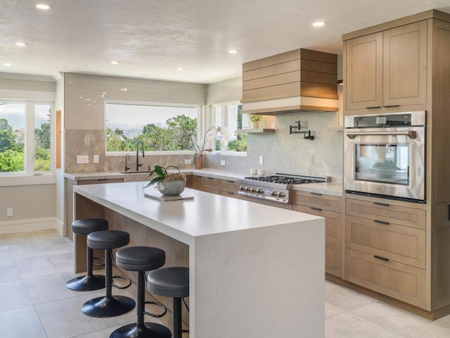 kitchen with a center island, appliances with stainless steel finishes, custom range hood, sink, and a breakfast bar area