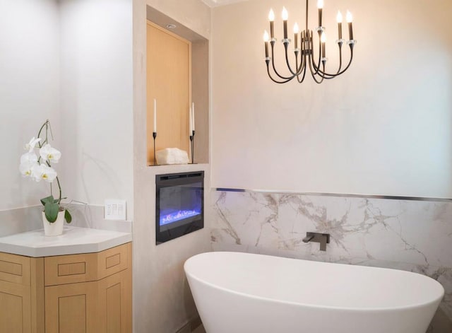 bathroom with an inviting chandelier, a bathing tub, tile walls, and vanity