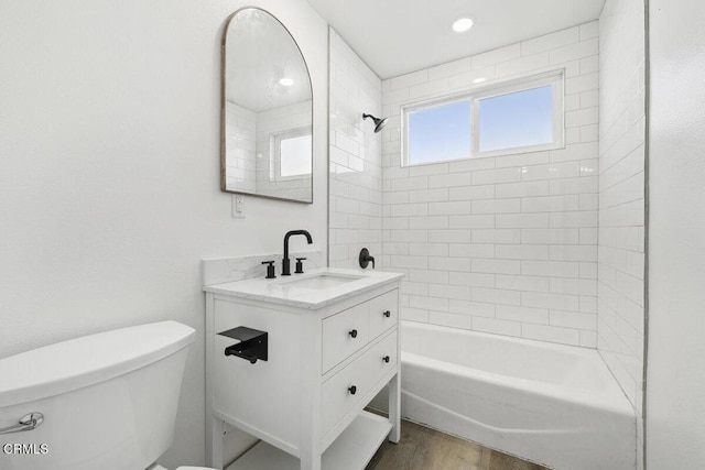 full bathroom with hardwood / wood-style floors, toilet, vanity, and tiled shower / bath