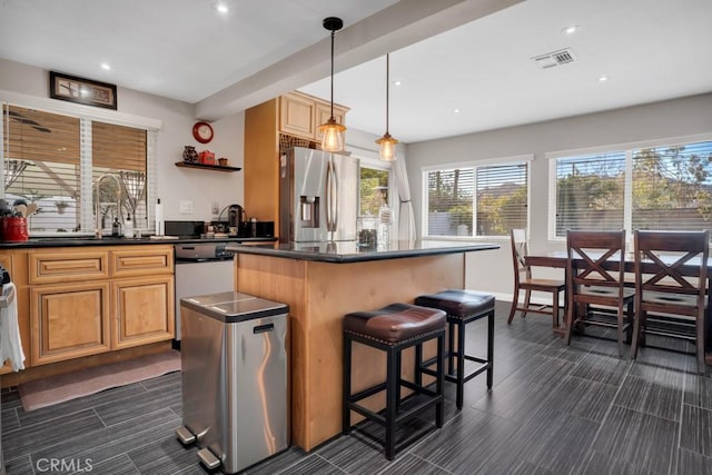 kitchen with appliances with stainless steel finishes, decorative light fixtures, sink, a kitchen breakfast bar, and a center island