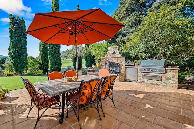 view of patio / terrace with exterior kitchen, an outdoor stone fireplace, and area for grilling