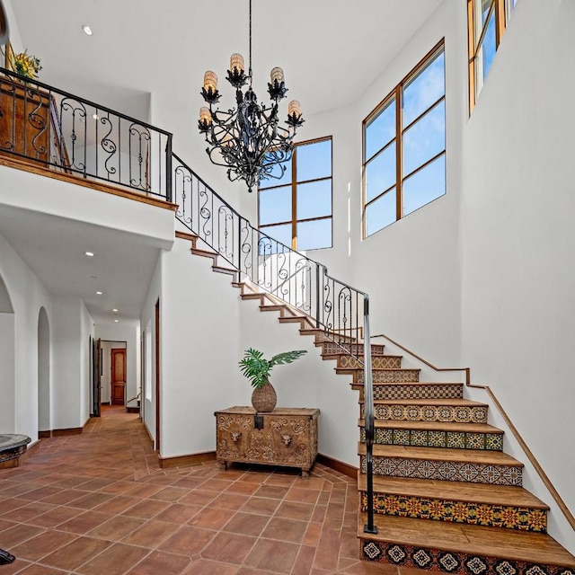 stairway featuring a high ceiling, tile patterned floors, and an inviting chandelier