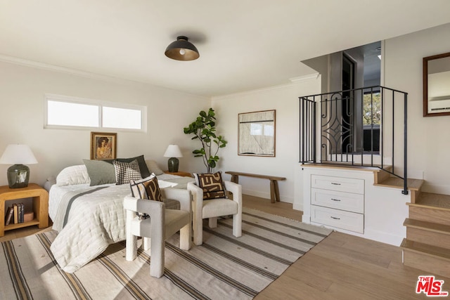 bedroom featuring multiple windows, ornamental molding, and light hardwood / wood-style flooring