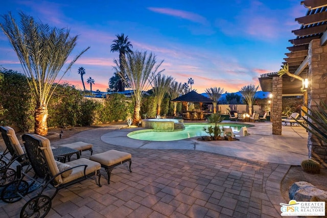 patio terrace at dusk with a pool with hot tub and a pergola