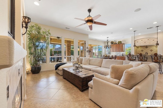 living room featuring ceiling fan with notable chandelier and light tile patterned floors