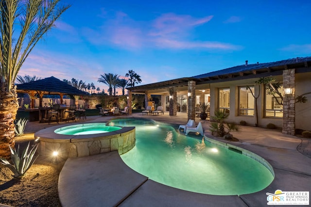 pool at dusk featuring an in ground hot tub, a patio, and a gazebo