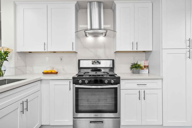 kitchen featuring wall chimney exhaust hood, white cabinets, sink, and stainless steel gas range