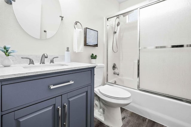 full bathroom featuring hardwood / wood-style floors, toilet, shower / bath combination with glass door, and vanity