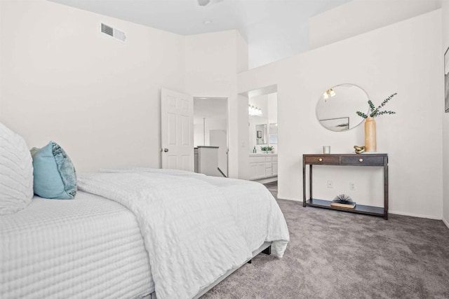 bedroom featuring dark carpet, connected bathroom, and a towering ceiling