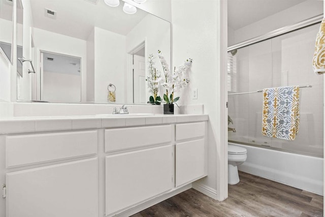 full bathroom featuring vanity, wood-type flooring, toilet, and combined bath / shower with glass door