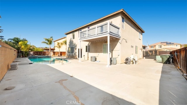 back of property with a fenced in pool, a balcony, and a patio area