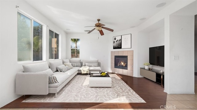 living room with a tiled fireplace, hardwood / wood-style flooring, and ceiling fan