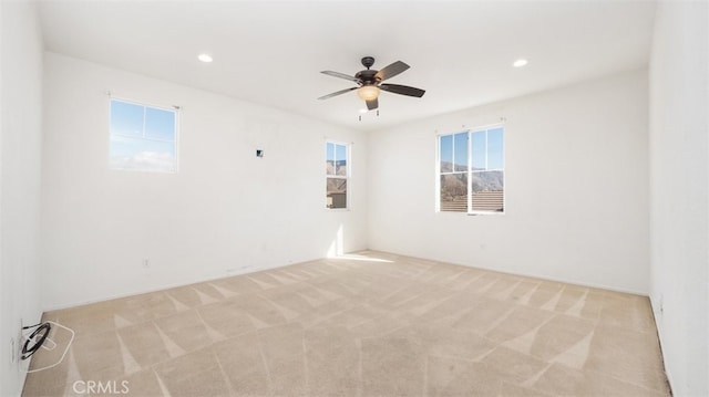 spare room with ceiling fan and light carpet