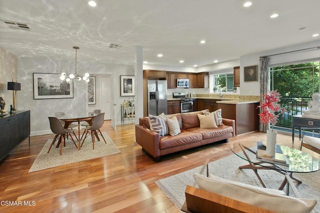 living room featuring a notable chandelier, light hardwood / wood-style floors, and sink