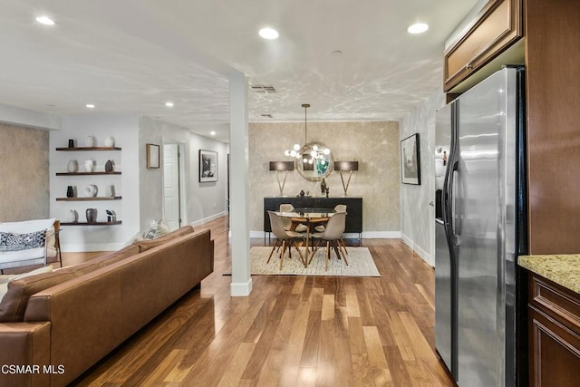 living room with light wood-type flooring and an inviting chandelier