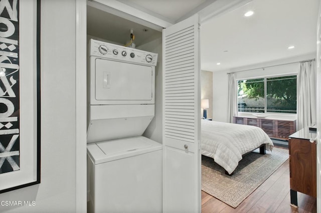 bedroom featuring stacked washer / dryer and hardwood / wood-style floors