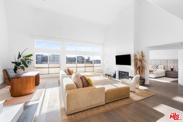 living room featuring light wood-type flooring and a towering ceiling