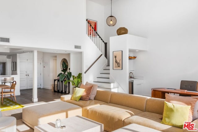 living room with wet bar, a high ceiling, and hardwood / wood-style floors