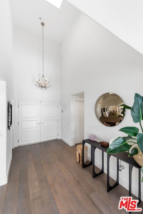 entrance foyer featuring high vaulted ceiling, dark hardwood / wood-style flooring, and a chandelier