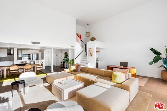 living room featuring light hardwood / wood-style floors and a towering ceiling