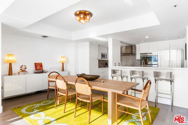 dining space featuring dark wood-type flooring and a tray ceiling