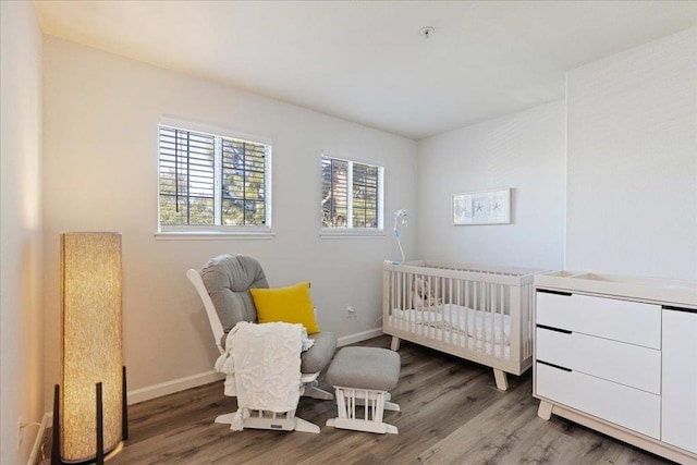 bedroom featuring hardwood / wood-style flooring and a nursery area