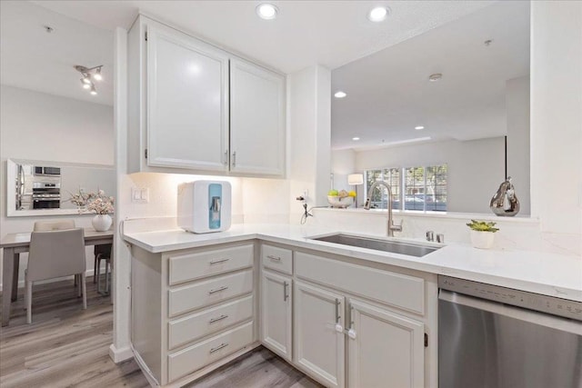 kitchen with sink, white cabinets, kitchen peninsula, stainless steel appliances, and light hardwood / wood-style flooring