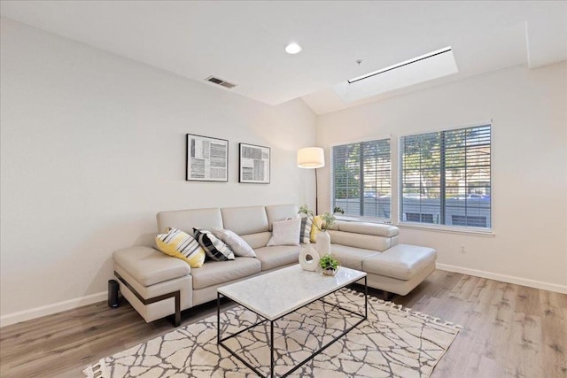 living room with hardwood / wood-style flooring and lofted ceiling with skylight