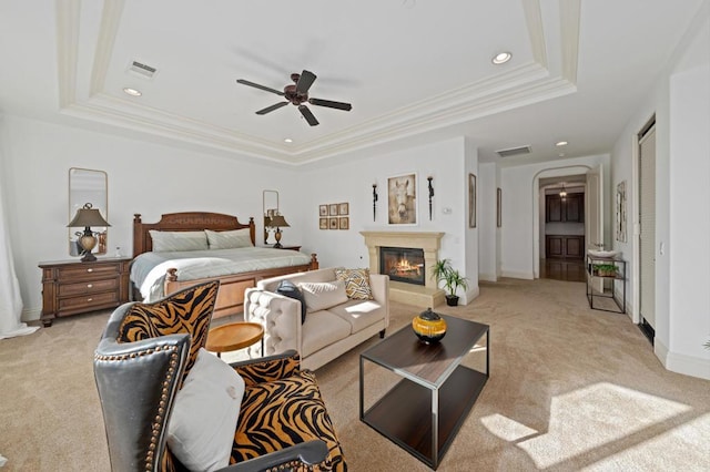 bedroom featuring ceiling fan, a raised ceiling, and light carpet