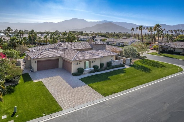 exterior space featuring a garage, a mountain view, and a front yard