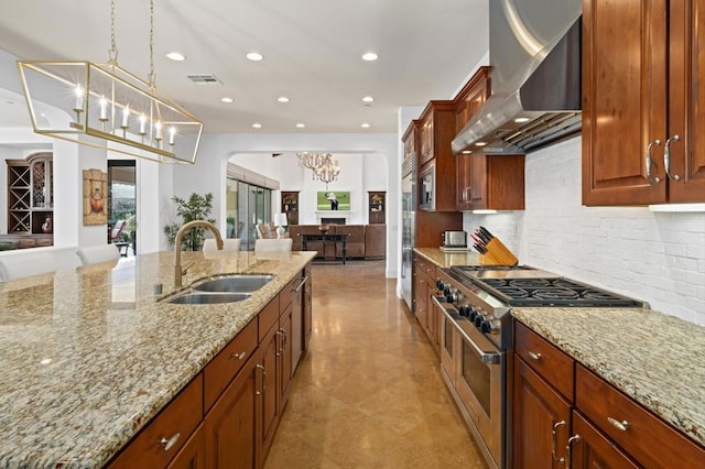 kitchen featuring wall chimney exhaust hood, sink, double oven range, a notable chandelier, and light stone countertops