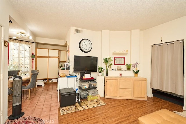 living room with a textured ceiling and light wood-type flooring