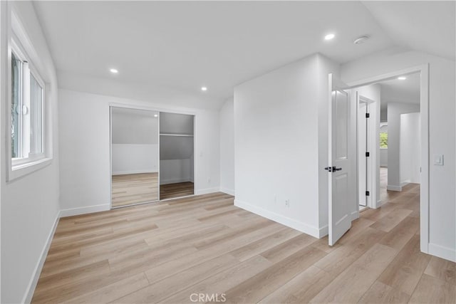 interior space with a closet, vaulted ceiling, and light hardwood / wood-style flooring