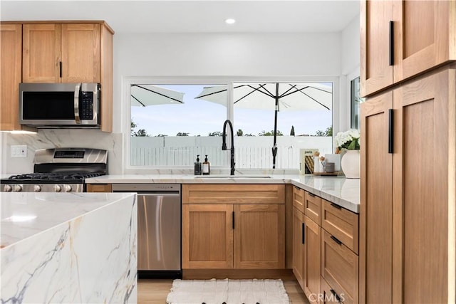 kitchen featuring light stone countertops, sink, a wealth of natural light, and appliances with stainless steel finishes