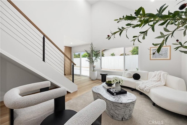 living room with light wood-type flooring and a towering ceiling