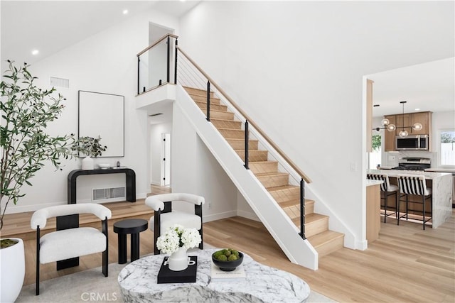 stairway featuring high vaulted ceiling and hardwood / wood-style floors