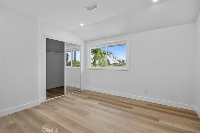 unfurnished bedroom with light hardwood / wood-style floors, a closet, and lofted ceiling