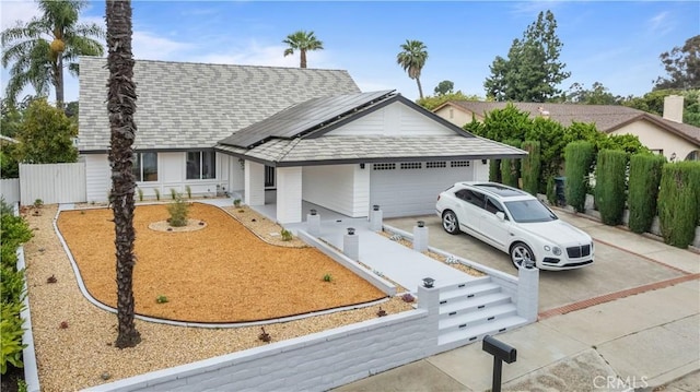 ranch-style house featuring a garage and solar panels