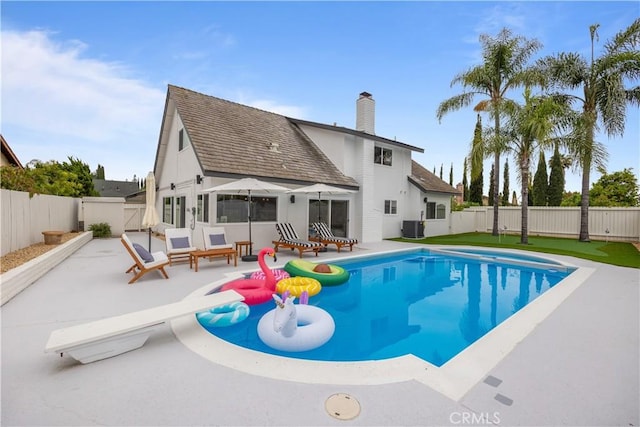 view of pool with a diving board, a patio area, and central AC