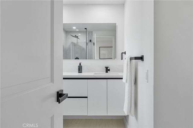 bathroom with a shower with door and vanity