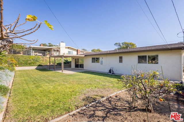 rear view of property featuring a yard and a patio